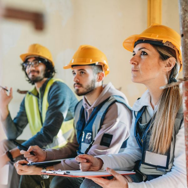 Three people are listening to their foreman on a construction site